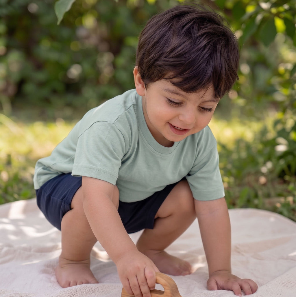 Child playing with a wooden toy outdoors on a blanket